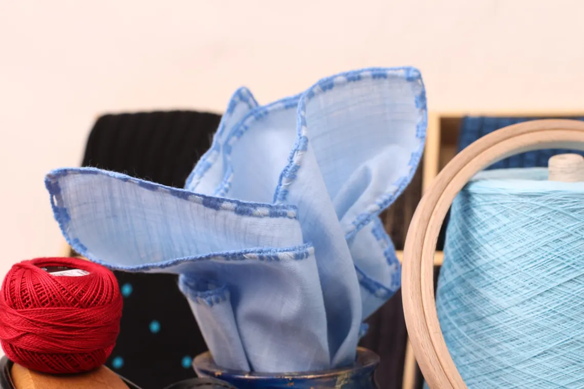 Blue linen pocket square with hand rolled edges, displayed neatly folded.