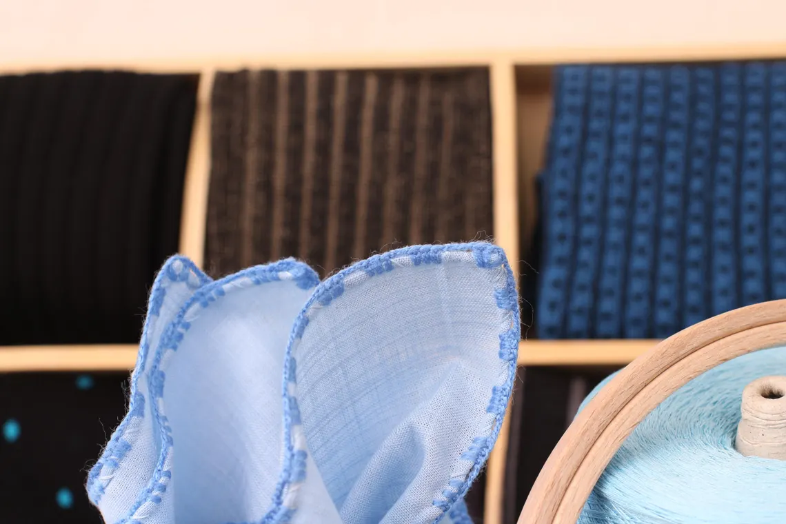 Elegant blue linen handkerchief laid flat to show texture and craftsmanship.